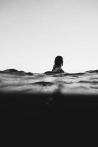 Black and white photograph of person facing away in ocean