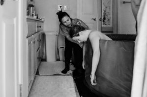 Person birthing with midwife in bathroom