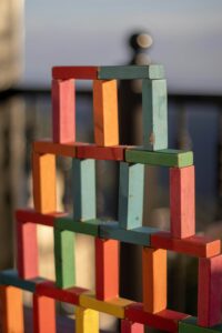 a tower is built by colorful blocks--red, orange, blue, and green